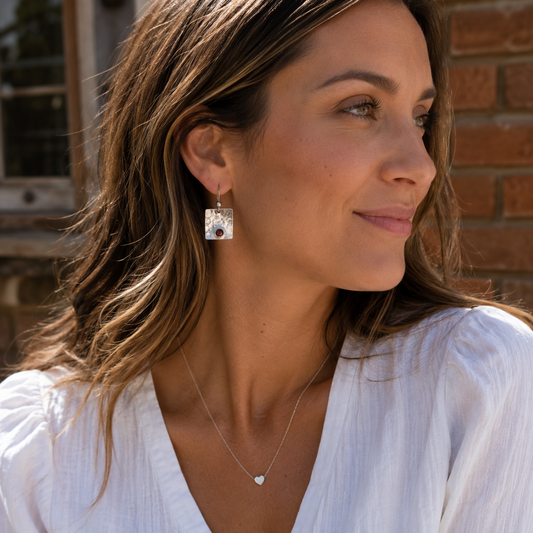 Woman wearing handcrafted sterling silver garnet drop earrings outdoors