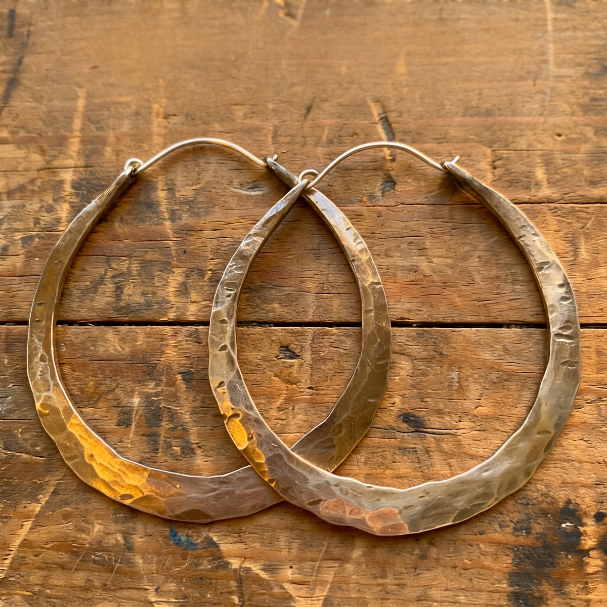 Handmade hammered sterling silver teardrop hoop earrings on rustic wood